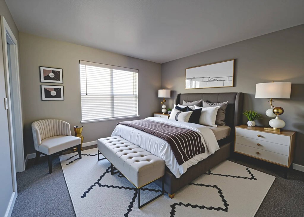 A bedroom with a large bed, a chair, and a nightstand.