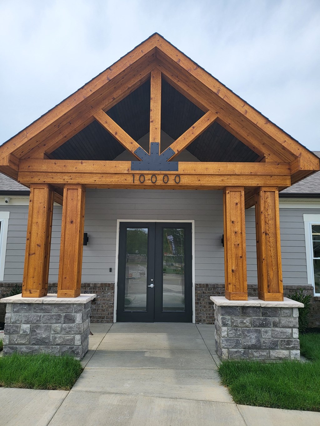 the front entrance of a building with a porch with wood beams and stone pillars