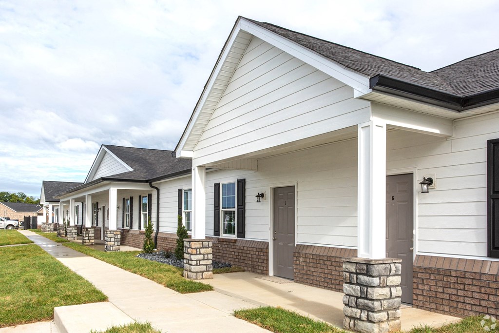 a row of white houses with a sidewalk and grass