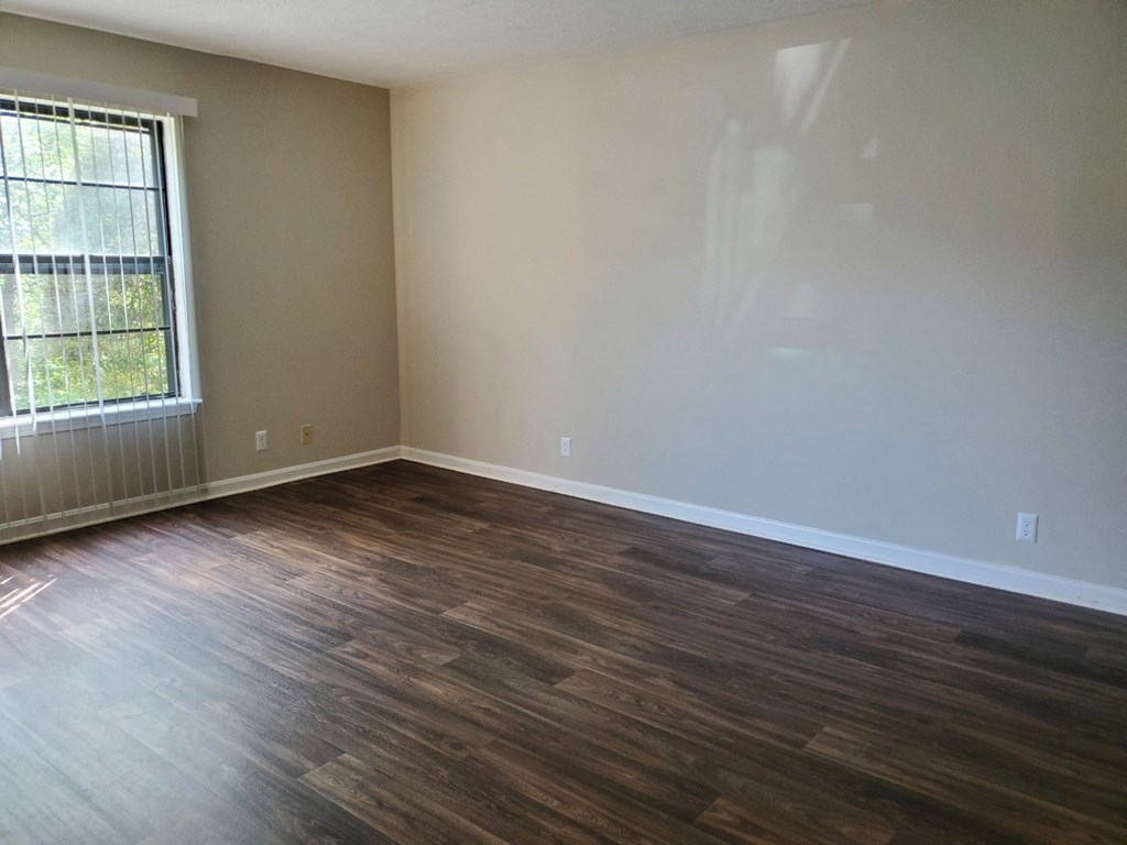 an empty room with wooden floors and a window