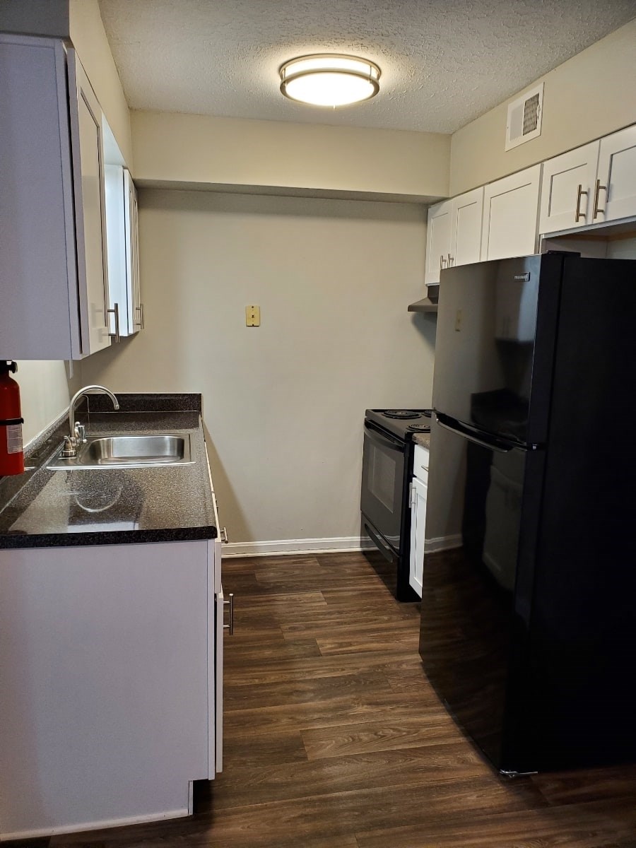 A kitchen with a black refrigerator and a black counter top.