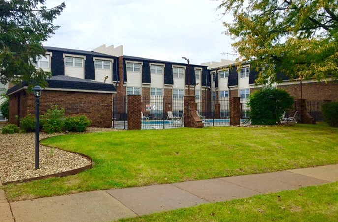 a building with a yard and a pool in front of it