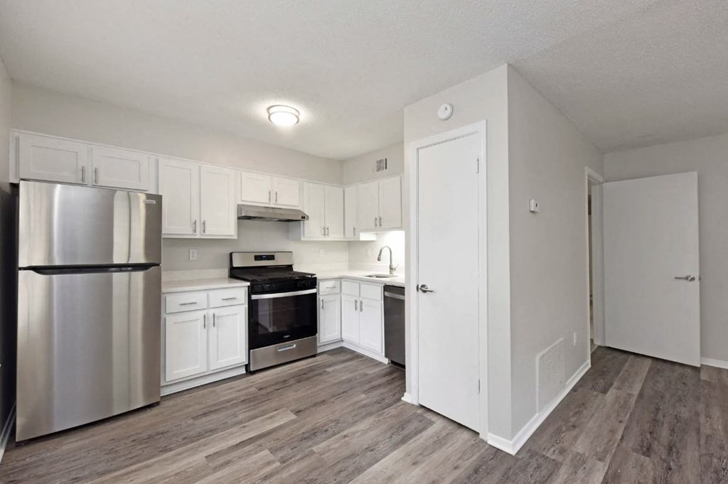 an empty kitchen with white cabinets and stainless steel appliances