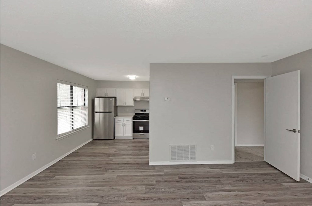 an empty living room and kitchen with a refrigerator and