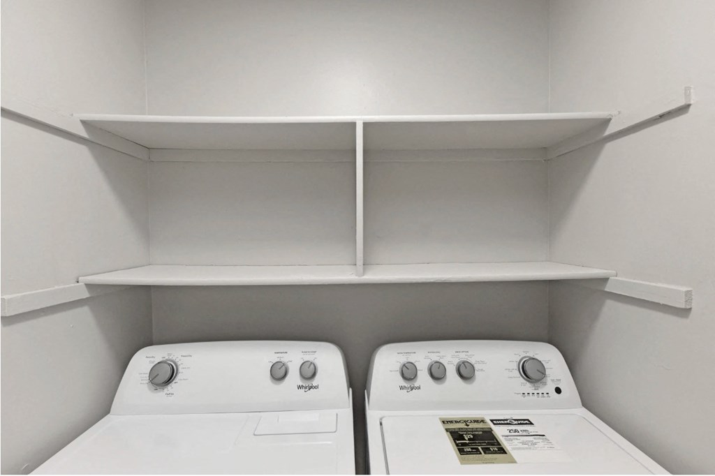 an empty laundry room with two washers and a dryer