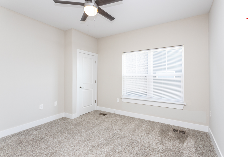 A room with a ceiling fan and a window with blinds.