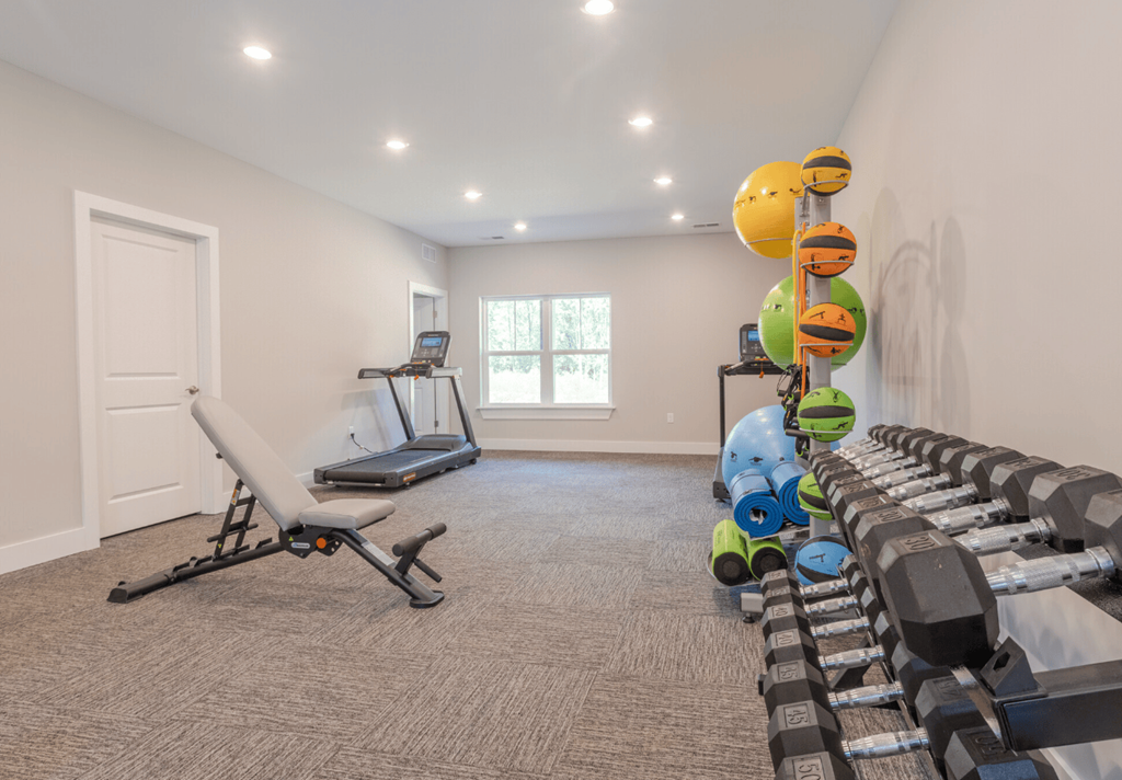 A room with a treadmill, exercise balls, and weights.