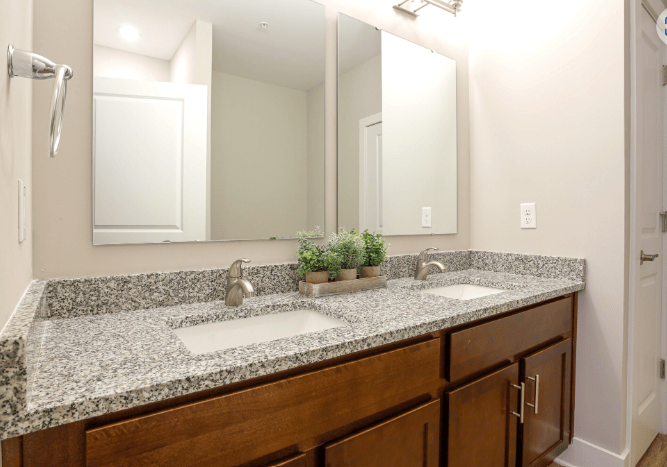 A bathroom with a granite countertop and a double sink.