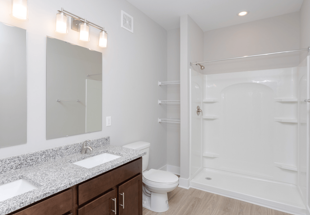 A white bathroom with a toilet, sink, and shower.