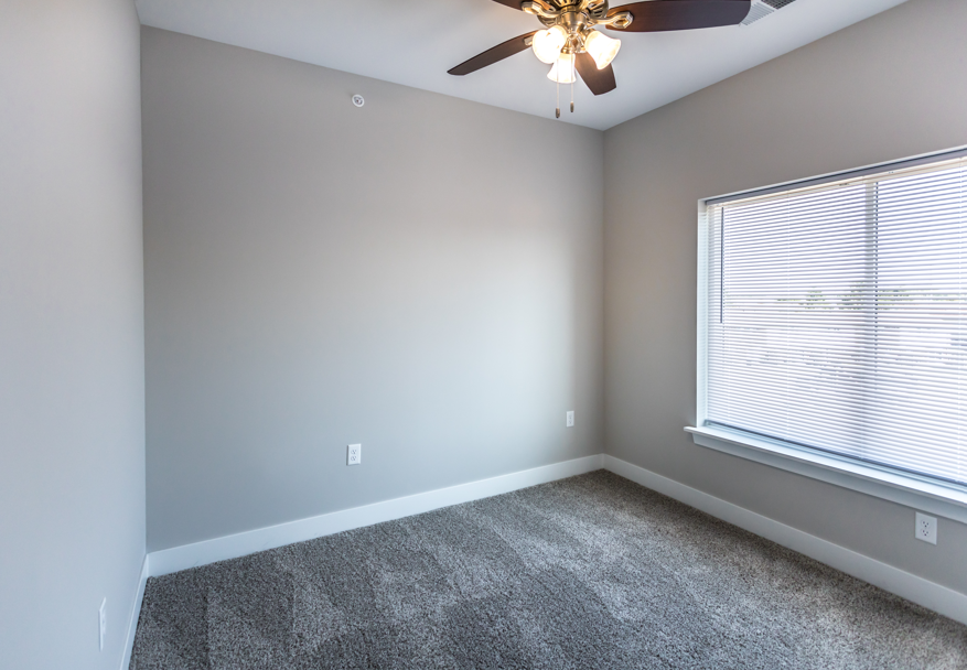 A room with a ceiling fan and a window with blinds.