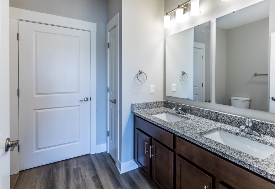 A bathroom with a white door, a mirror, and a sink.