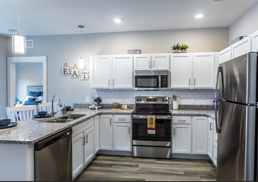 A kitchen with white cabinets and a black stove top oven.