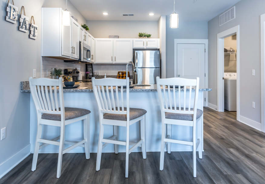 A kitchen with white chairs and a refrigerator.