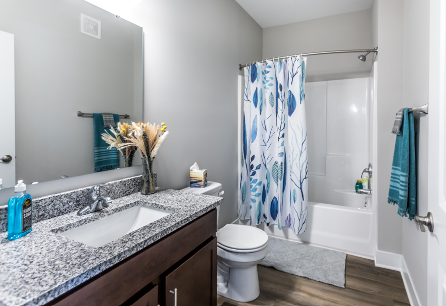 A bathroom with a white toilet, a sink, and a shower with a blue and white shower curtain.