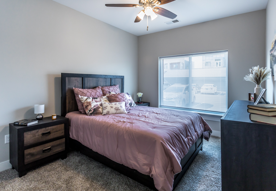 A bedroom with a bed, nightstand, and window.