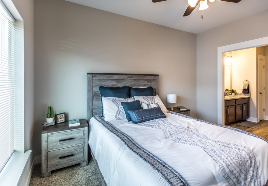 A bedroom with a large bed and a ceiling fan.
