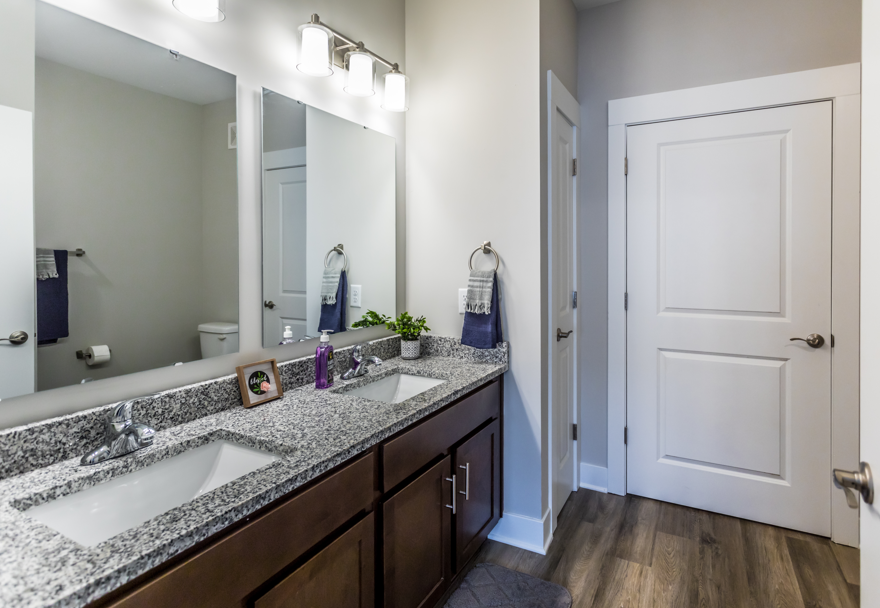 A bathroom with a white door and a mirror above the sink.