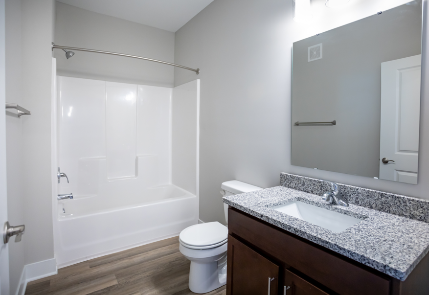 A white toilet sits under a mirror in a bathroom.