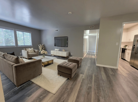 A modern living room with a grey sofa set and a television.