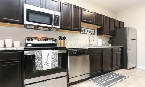 A kitchen with dark brown cabinets and stainless steel appliances.