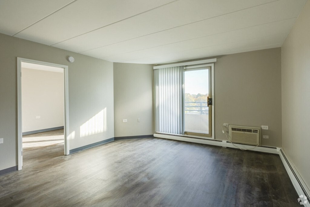 an empty living room with wood floors and a sliding glass door