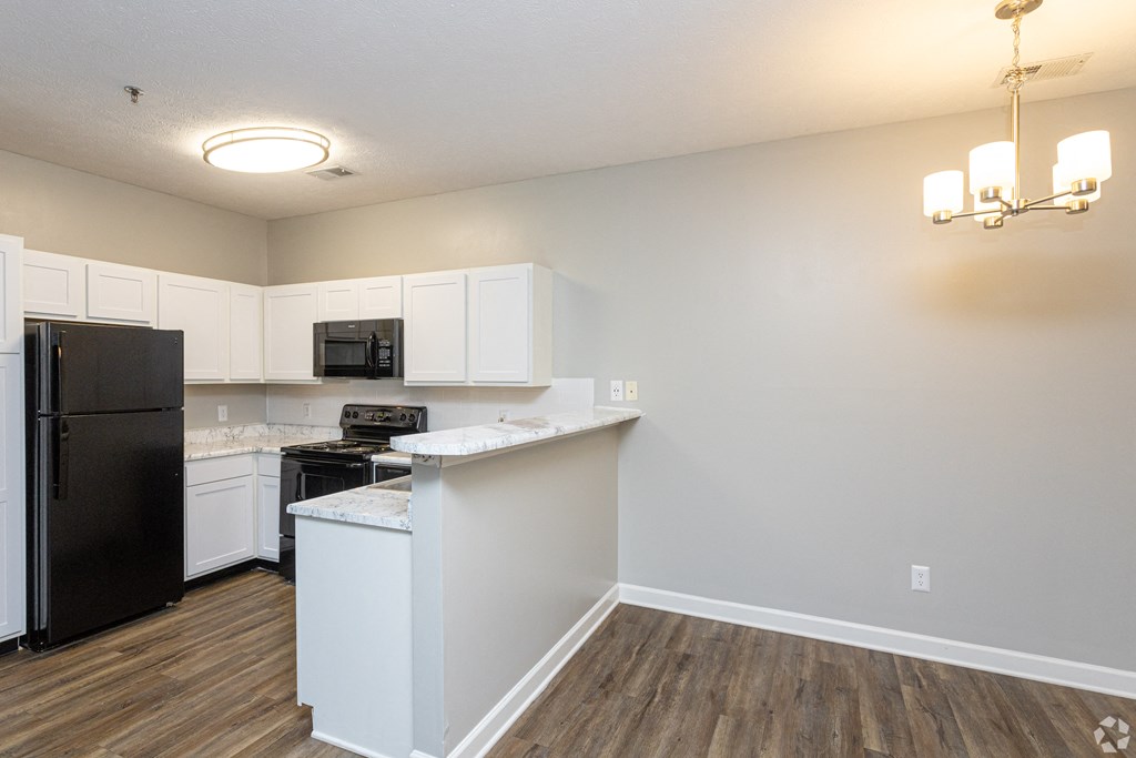 an empty kitchen with white cabinets and a black refrigerator