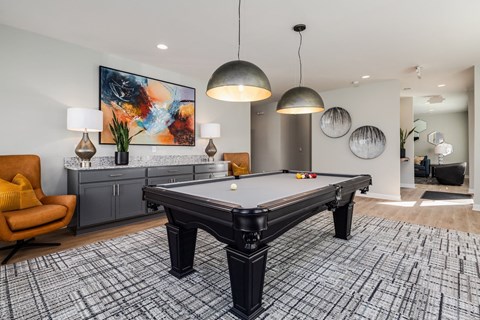 A pool table in a room with a chair and a painting on the wall.