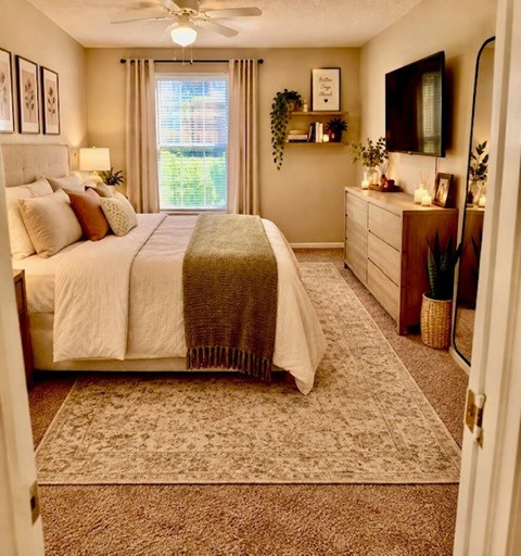 A bedroom with a large bed and a window with curtains.