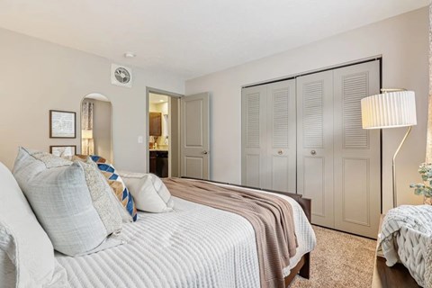 A bedroom with a bed, dresser and closet  at Avenue in the Highlands Apartments in Louisville