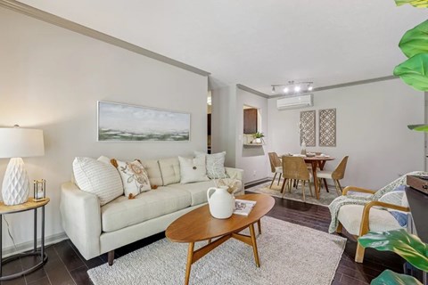 A living room with a white couch and a painting on the wall.