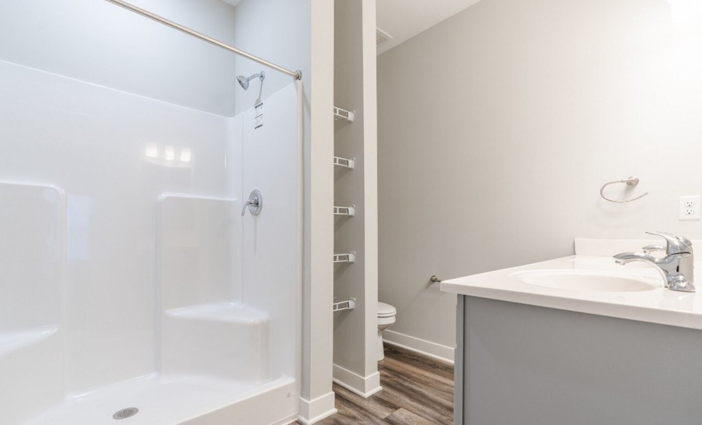 A white bathroom with a walk-in shower and a sink.