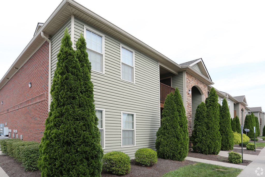 an apartment building with trees and shrubs in front of it