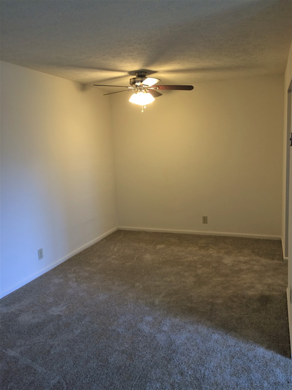 a living room with a ceiling fan and a carpet