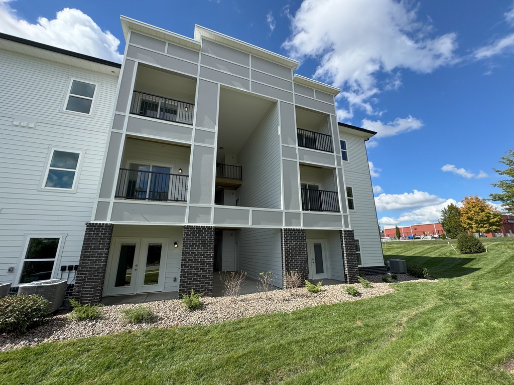 A white apartment building with balconies and a clear blue sky.