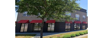 A building with red awnings and a tree in front.