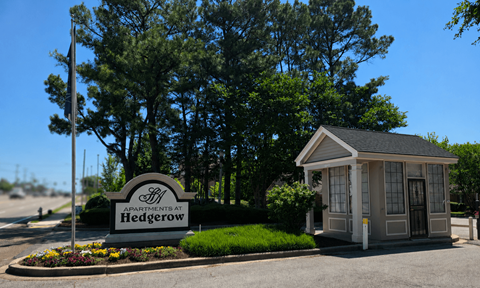 A small building with a sign that says Apartments at Hedgerow in front of it.