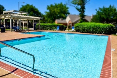 a large swimming pool with a pavilion and trees in the background