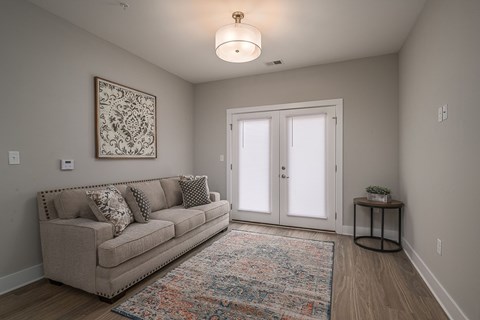 A living room with a couch, a rug, and a painting on the wall.