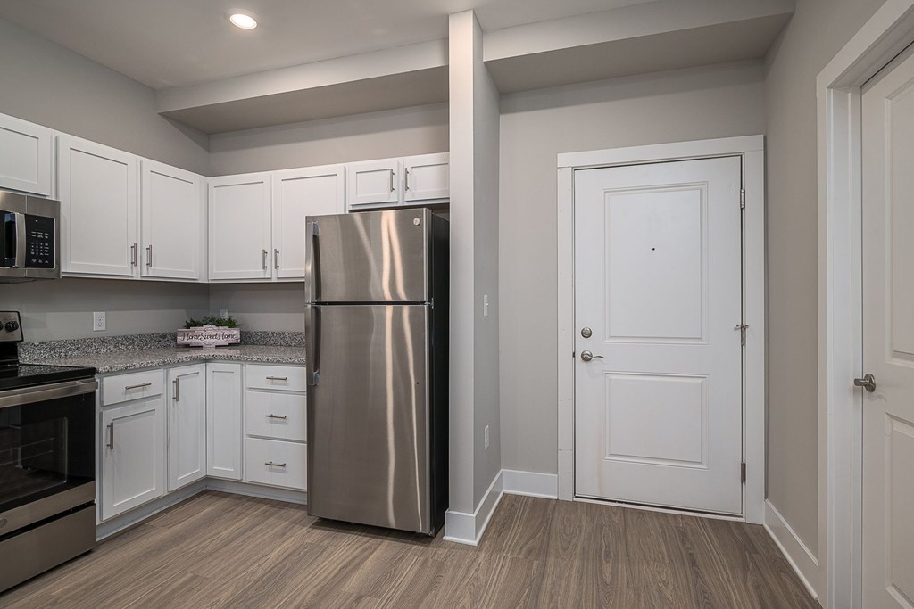 A kitchen with a stainless steel refrigerator and white cabinets.