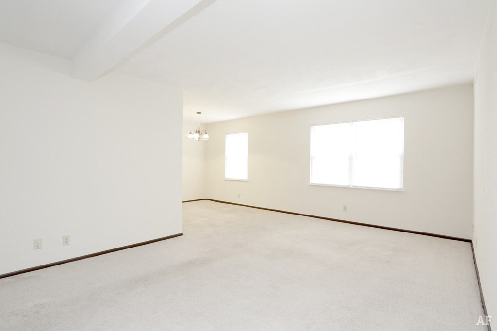 an empty living room with a white wall and a window