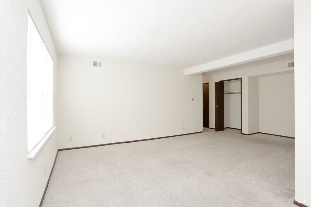 an empty living room with white walls and a door to a closet