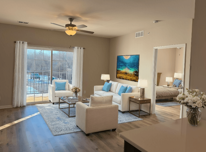 A living room with a white sofa set and a painting on the wall.