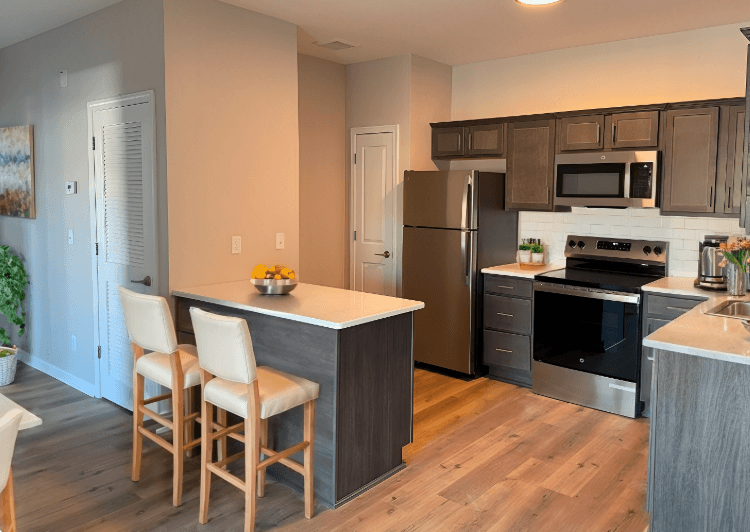 A kitchen with a white countertop and wooden chairs.