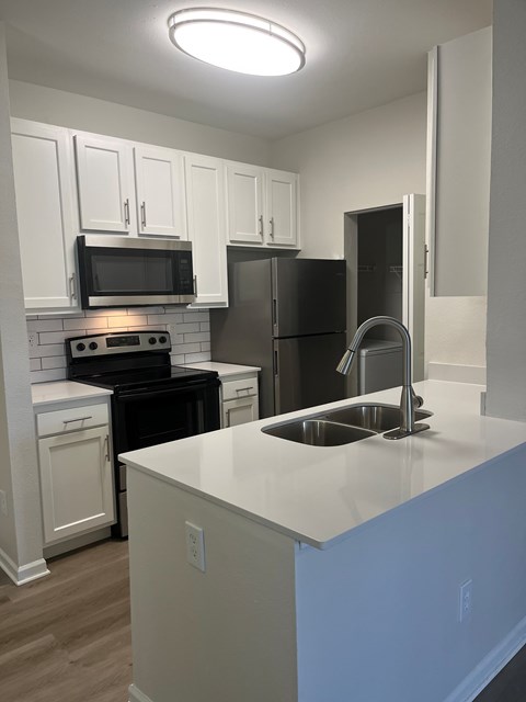 A kitchen with white cabinets and black appliances.