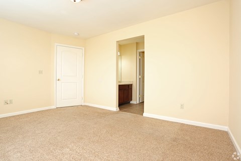 an empty living room with a door to a bathroom