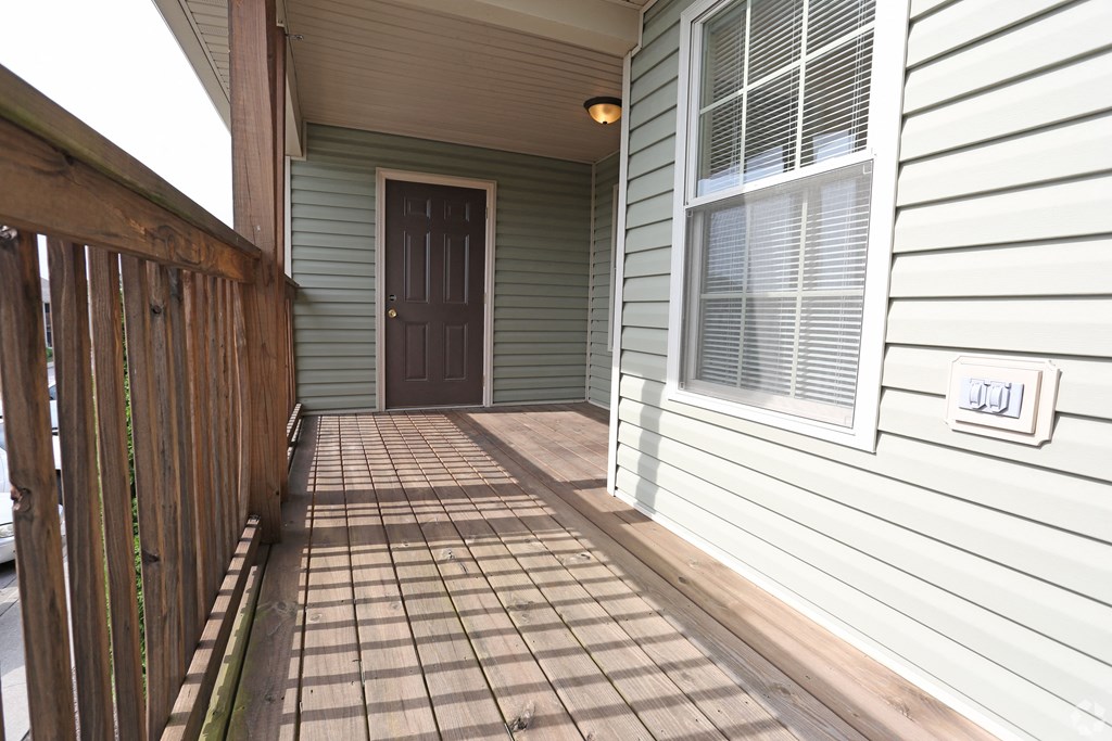 the front porch of a house with a brown door