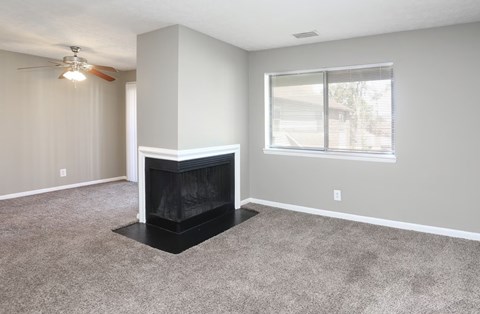 A living room with a fireplace and a ceiling fan.