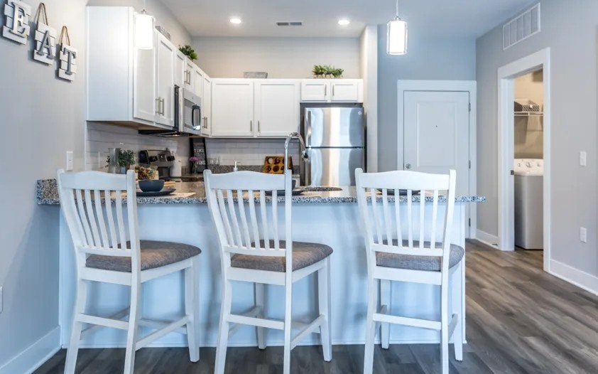 A kitchen with white chairs and a counter.