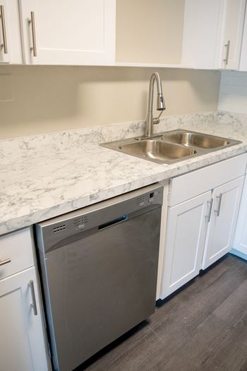 a kitchen with white cabinets and a sink and a dishwasher