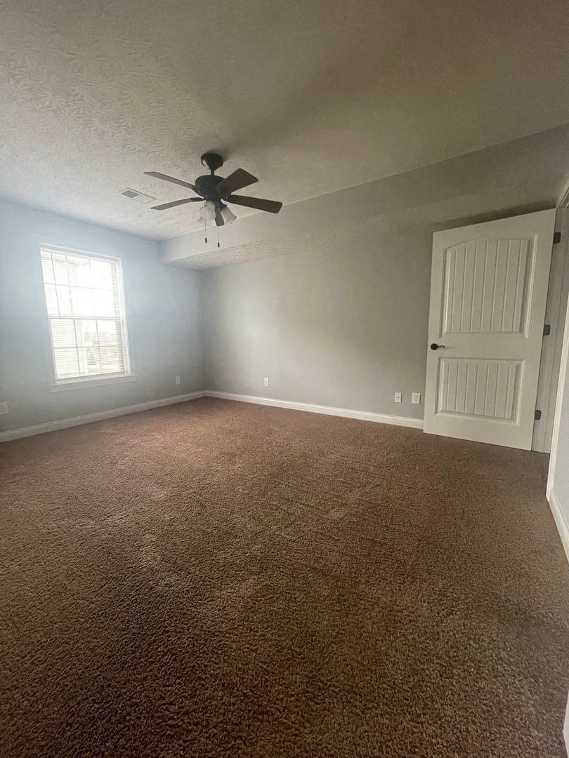 an empty room with a ceiling fan and a white door